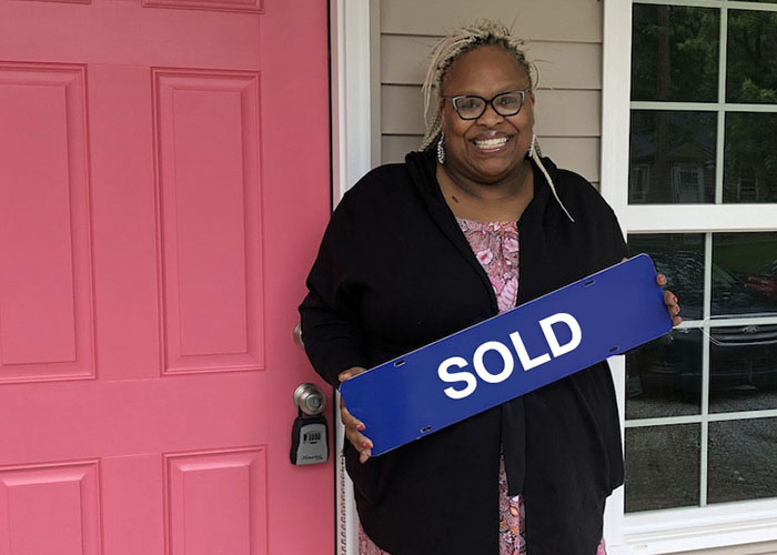 Female homeowner holding "sold" sign