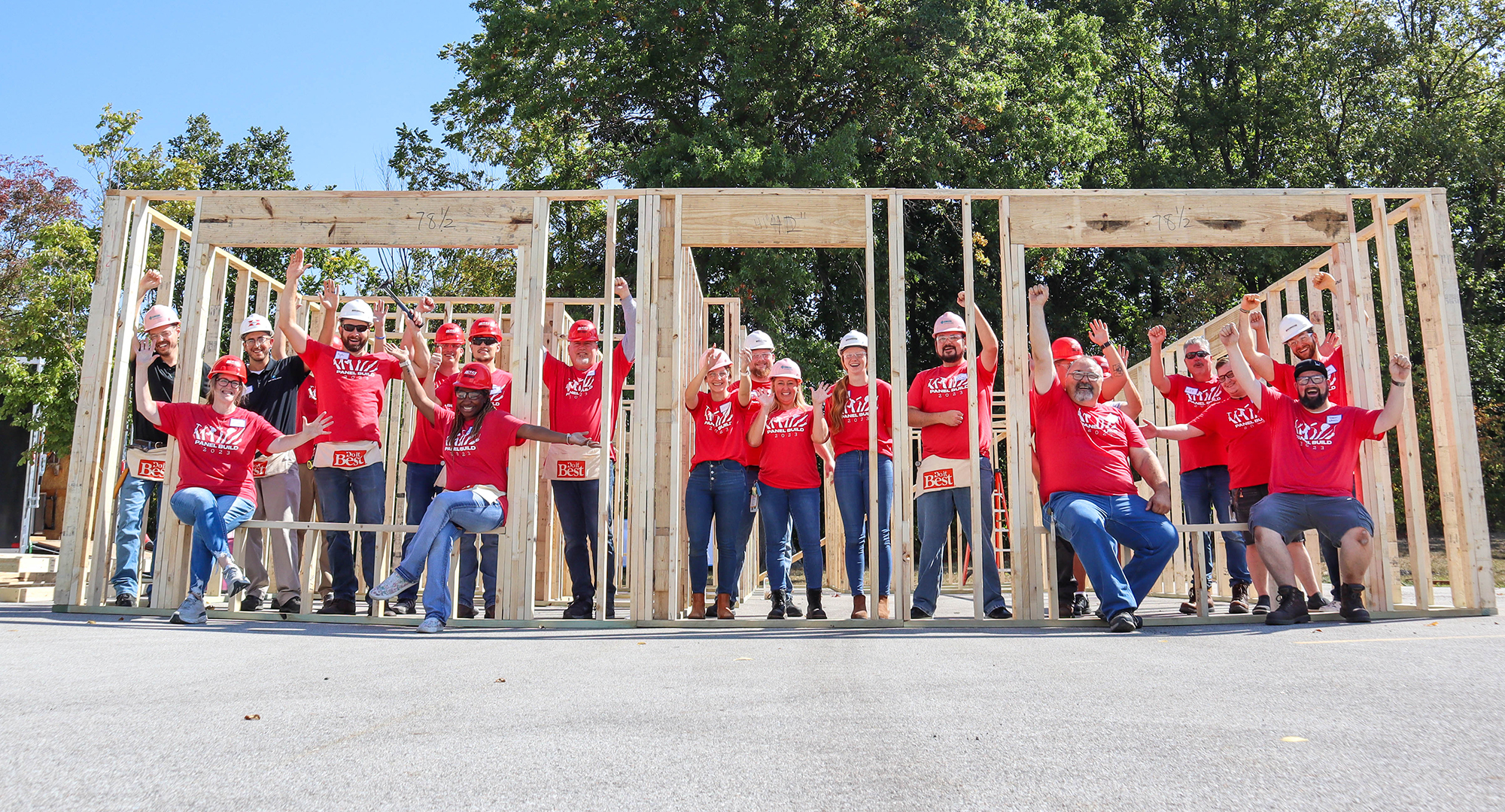 Group of volunteers cheering in front of walls of a home