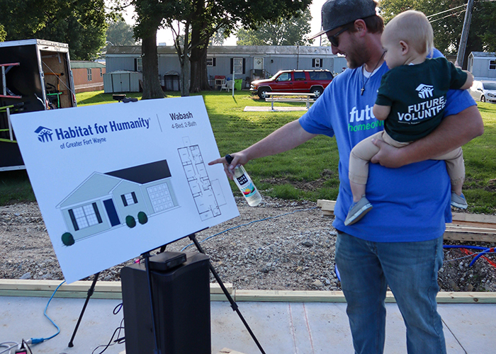 Dad and son pointing to Habitat home floor plan sign