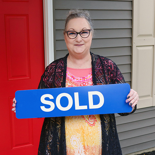 Woman holding "Sold" sign