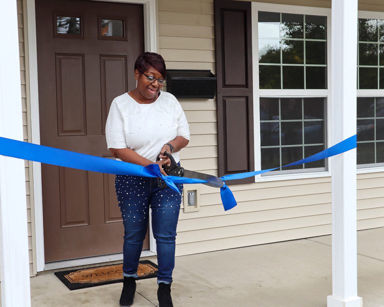 Woman cutting ribbon on her house