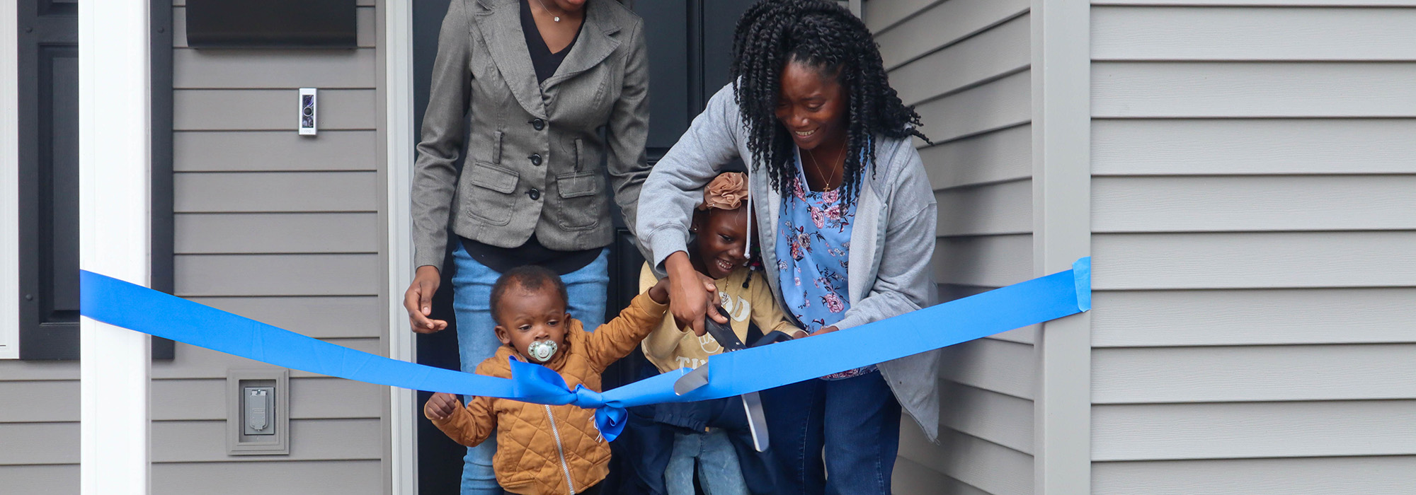 Family cutting a ribbon on their new house
