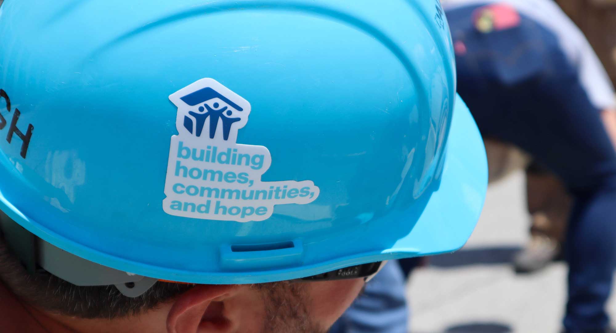 Hard hat with sticker that reads "building homes, communities, and hope"