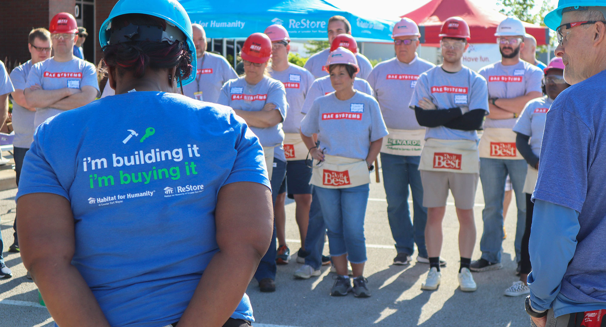 Partner Family with "I'm Building it, I'm Buying it" on the back of her shirt — standing in front of volunteers