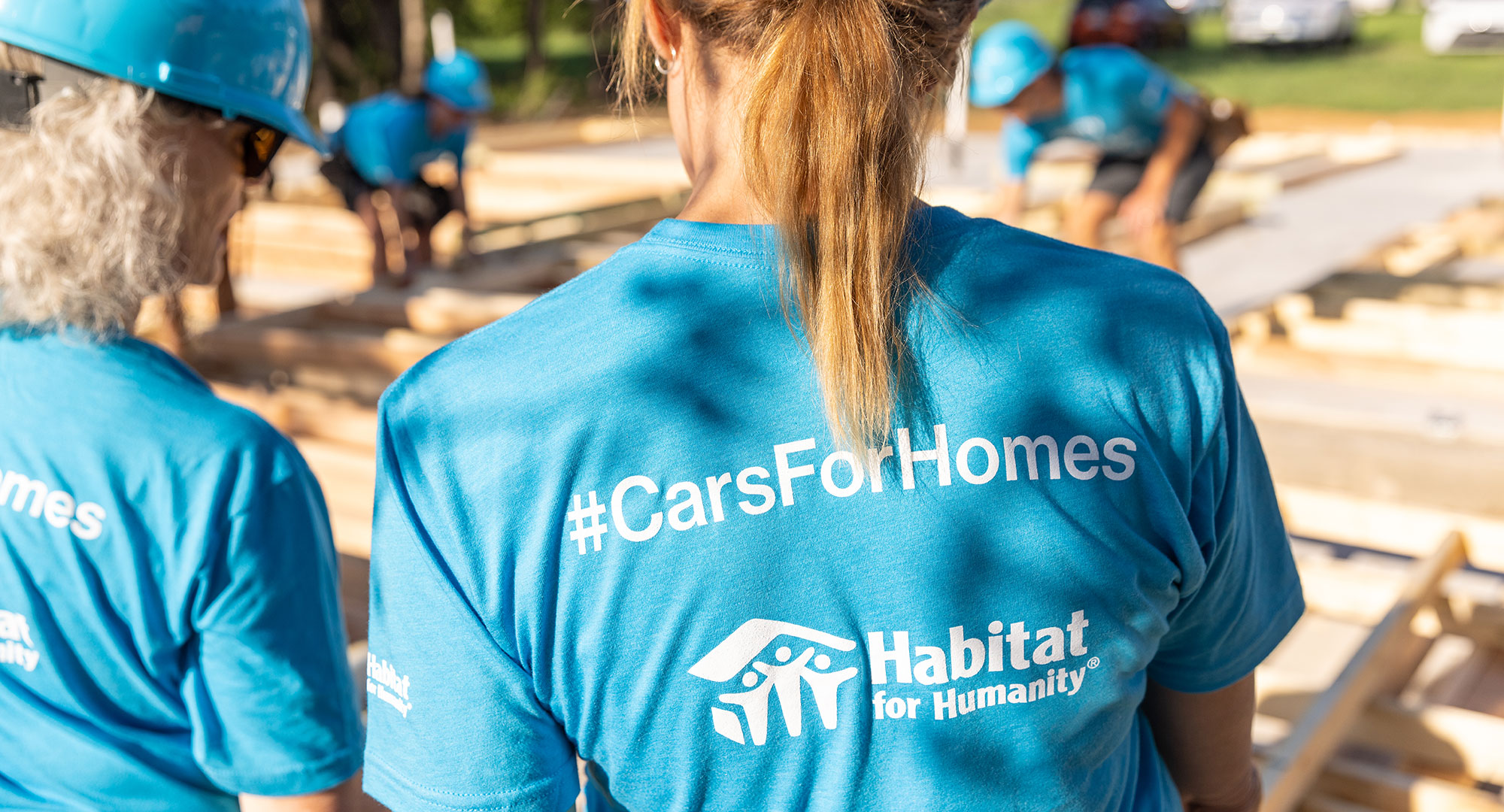 Back of woman's shirt with Habitat for Humanity logo and "#CarsForHomes"