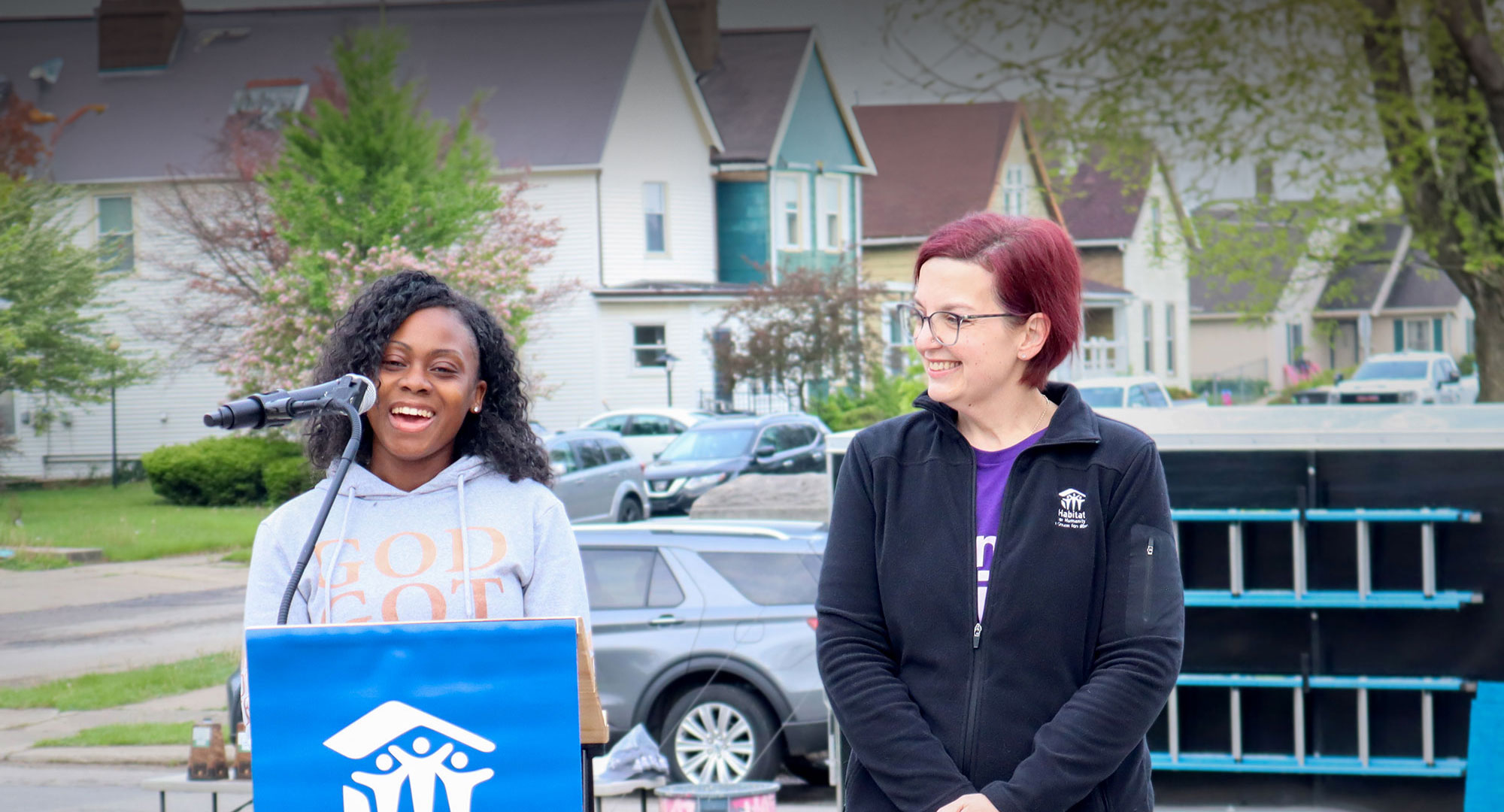 Tiffany, Future Homeowner, at microphone standing next to Lauren, Habitat staff