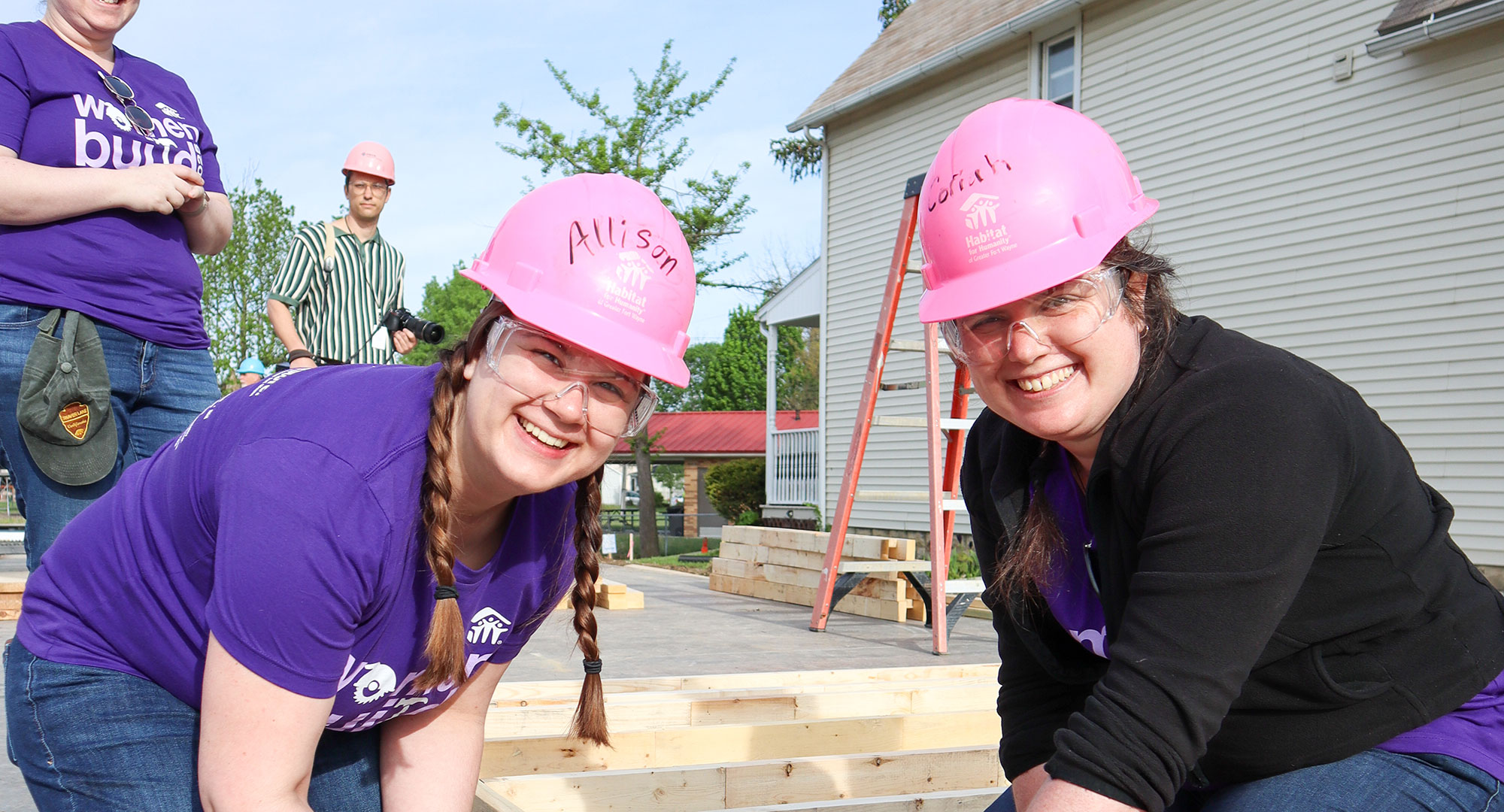 Two women with pink hard hats smiling at camera